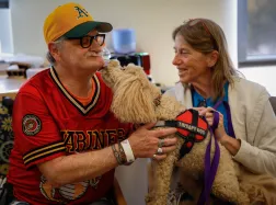 Gerry Gregg, Marine veteran from Sacramento, pets Sophie O’doodle, the 8-year-old doodle, next to her handler Claire Rhodes, San Jose, during a Furry Friends Pet Assisted Therapy session at the Palo Alto VA Medical Center in Palo Alto, Calif., on Monday, Oct. 27, 2025. (Shae Hammond/Bay Area News Group)