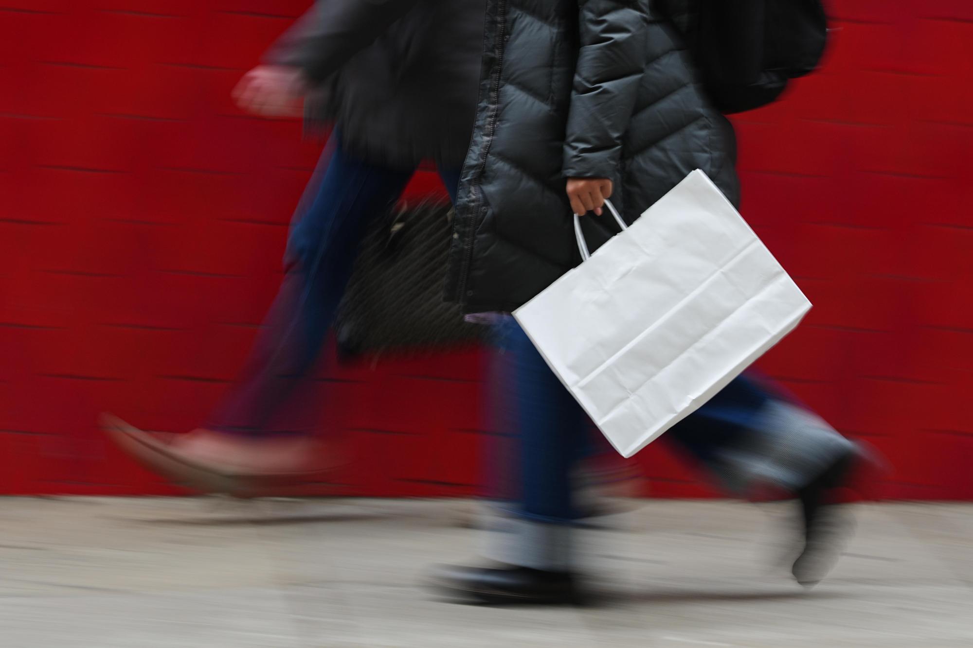 Climate_Choices_Holiday_Returns_36471-1 FILE – A person carries a shopping bag in Philadelphia, Dec. 10, 2025. (AP Photo/Matt Rourke, File)