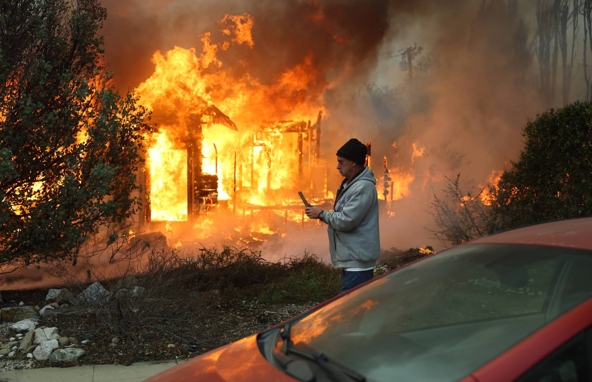 PAS-L-EATONFIRE-DAY2-0109-80 A person walks past a home burning during the Eaton Fire on Jan. 8 in Altadena.